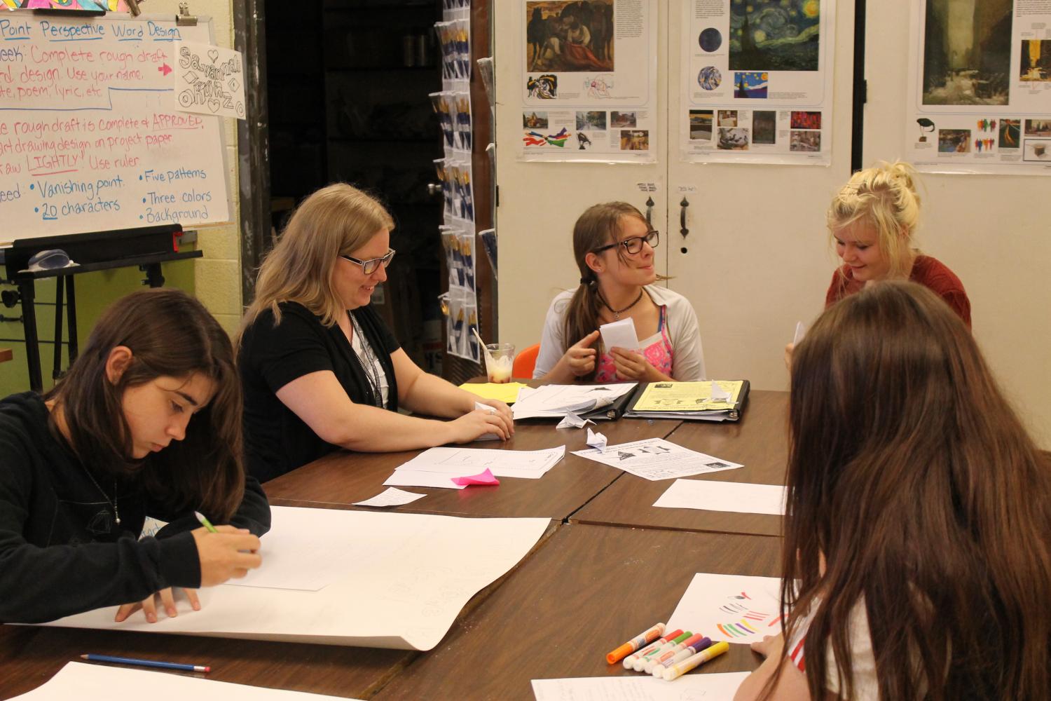 Mrs. Morie is teaching her daughter Savannah Kunz and Malayna Elrod how to make paper origami cranes while Anna Robbins and Ella Sikes work on posters for Anime Club.