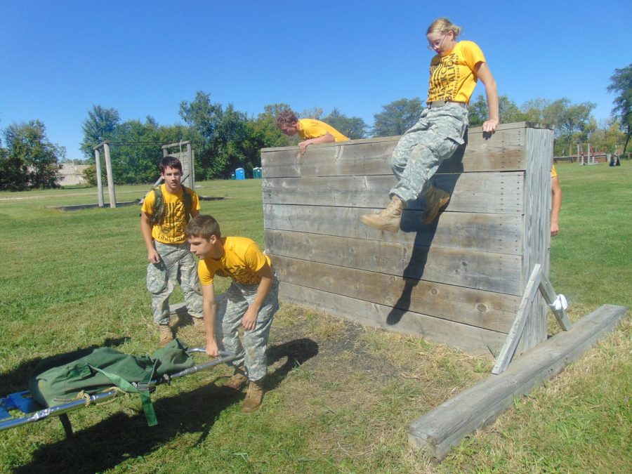 Aaron Cooper stands ready to assist team members as Caleb Cooper picks up the back end of the stretcher. Jerritt Hargis scales his end of the wall, while senior Abby Lee is already up and over.