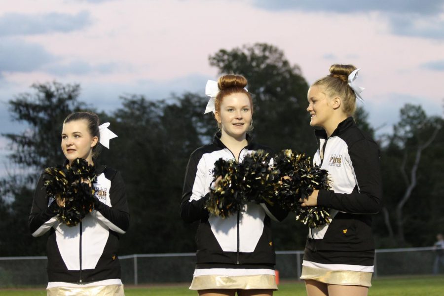 Freshman Paxton Clark and sophomores Stella Steck and Maddie Jennings prepare to greet the football players as they run out of the tunnel at the De Soto homecoming game.
