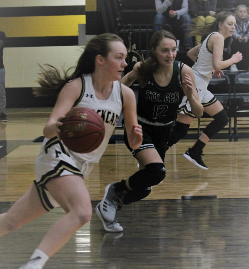 Mallory Mathes, Junior dribbles the ball to the other side of the court after a rebound.  Senior Maddie Burrows remains ready to receive a pass. 