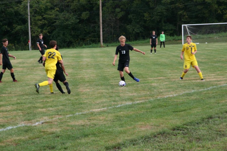 Will Arras, senior, dribbles the ball in between two opponents. 