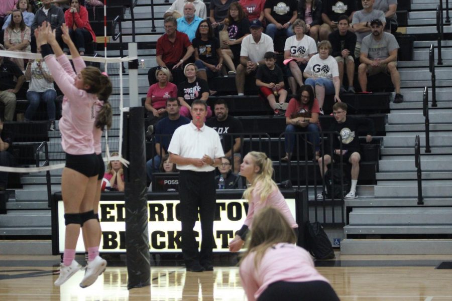 Freshmen Lydia Mell and Freshmen Linley Rehkop soar up with their arms reaching up in an attempt to get the ball back to the other side and score a point.  