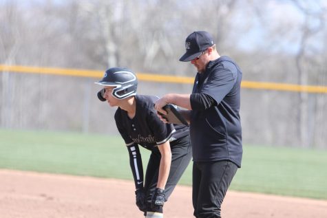Coach Huff discussing plans with Caleb Sarakas (12) as he catches his breathe at 1st base.