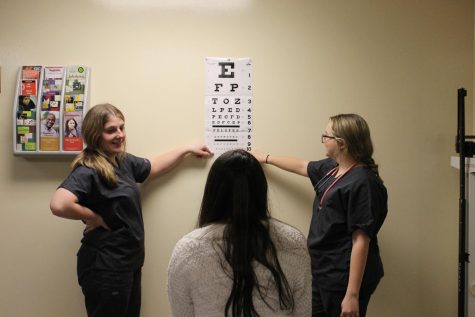 Lizzy Cureton (11) and Brianna Stacey (11) practicing how to give an eye exam on a patient. 