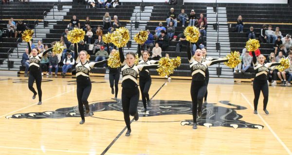2023-2024 Gold Dusters performing their pom routine at a girls basketball game. 