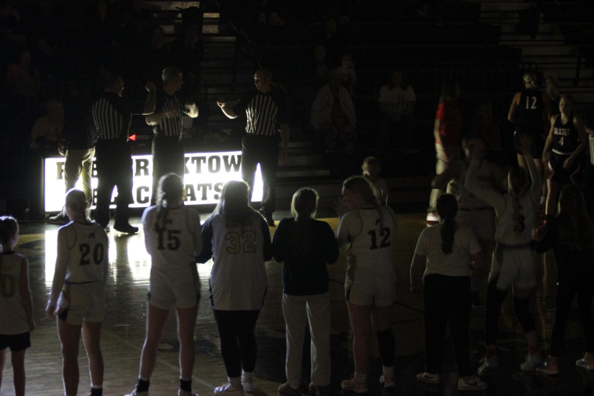 The present and future Lady Cats facing the crowd while the last teammate runs onto court. 