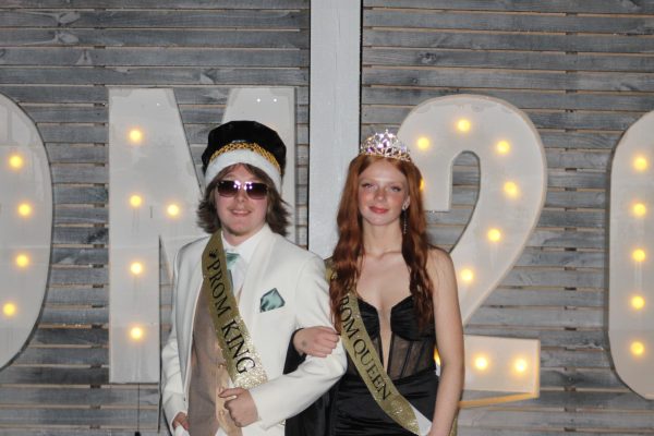 Gage Betts and Grace Lewis posing in front of the prom sign after being announced king and queen. 